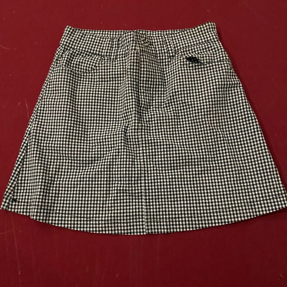 Small checkered black and white mini skirt. Has posters and zippers and buttons!